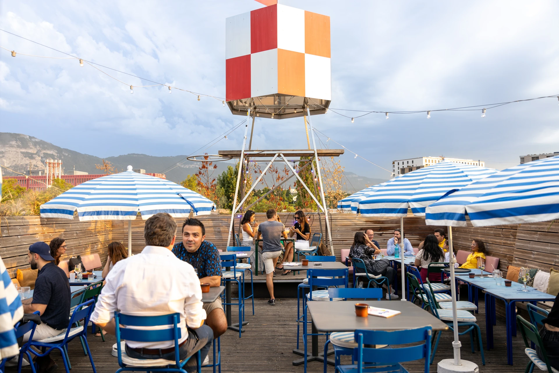 Terrasse du Rooftop 105 à Genève, parasols bleus rayés et château d'eau signature au-dessus de la Praille